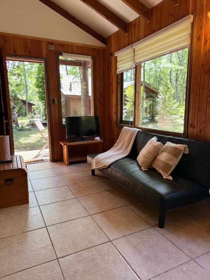 Sala de estar de la Suite Tuwa con sofá y ventanales al bosque
