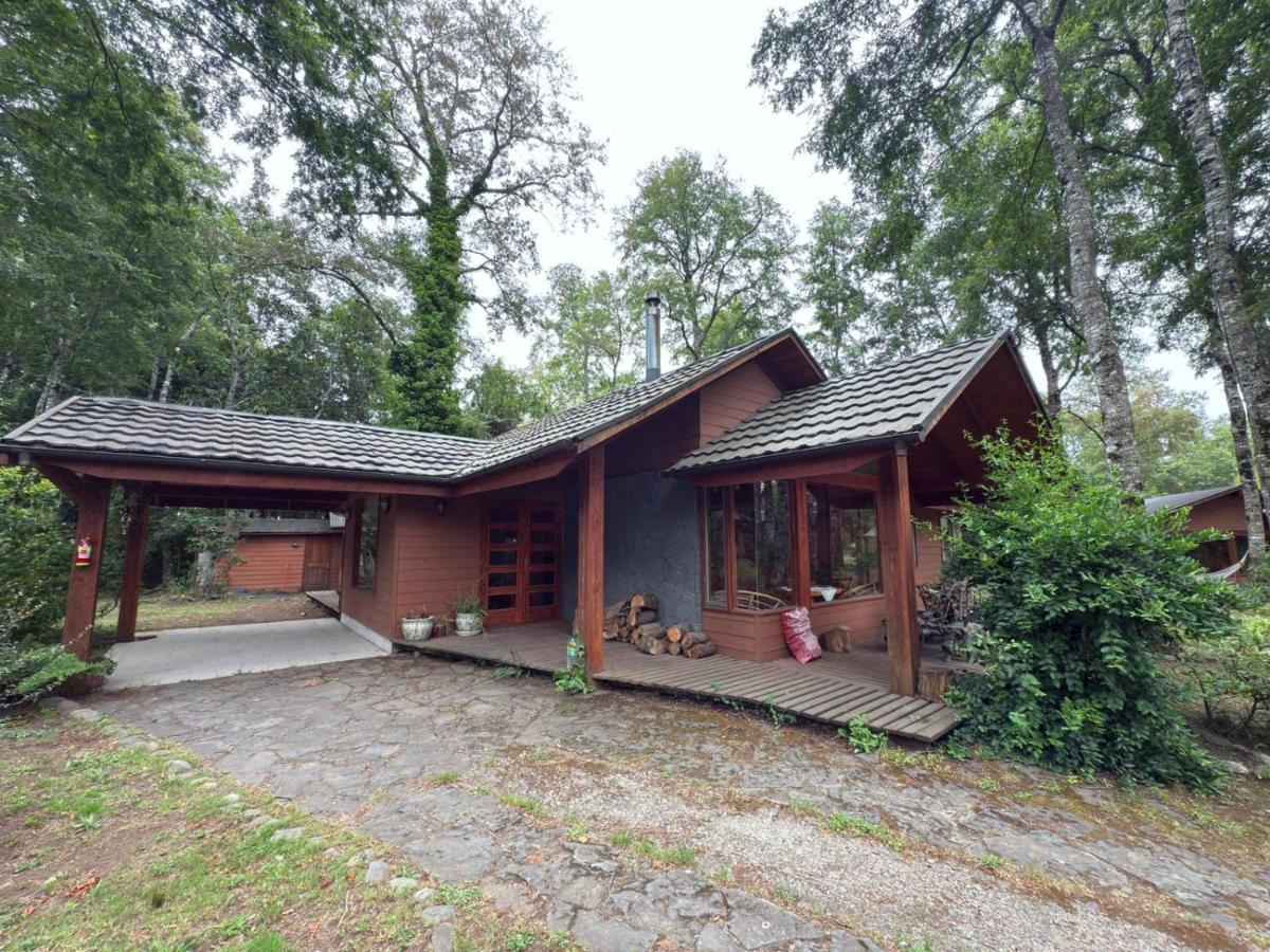Fachada de la Casa del Bosque con leña en la entrada