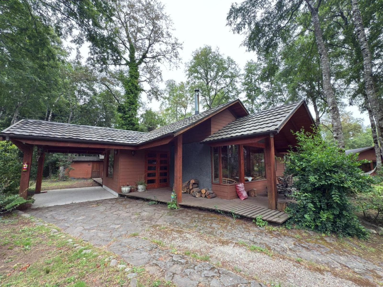 Fachada de la Casa del Bosque con leña en la entrada